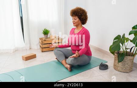 African senior woman doing yoga session at home - Healthy lifestyle and body positive concept - Focus on face Stock Photo