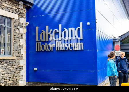 Exterior view of the lakeland motor museum, with a large collection of vintage cars and vehicles, with large font logo and text sign against blue wall Stock Photo