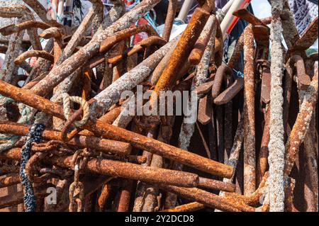 A stack of rusty steel anchors with ropes, chains and barnacles on the shore at Hastings, England Stock Photo
