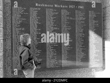 A Caucasian woman, 55 to 60 years, viewing a Mount Rushmore workers sign at the National Memorial in South Dakota, USA. Stock Photo