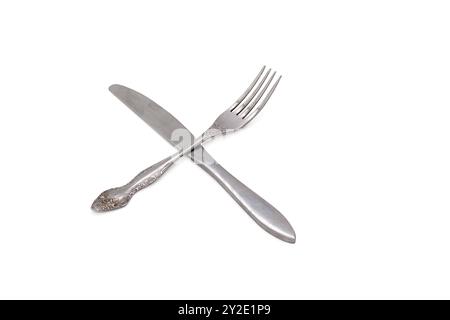 Metal fork and table knife lying crosswise on white isolated background. Restaurant etiquette. Horizontal. Stock Photo