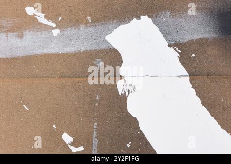 Background with random white paint strokes on brown cardboard with splashes of black paint Stock Photo