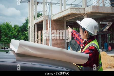 Engineers checking blueprint and planning project working outdoors building side on a worksite, Engineering and architecture concept, Engineer working Stock Photo