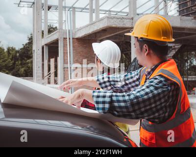 Team engineers checking blueprint and planning project working outdoors building side on a worksite, Engineering and architecture concept, Engineers h Stock Photo