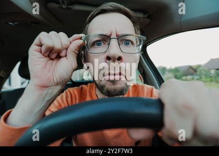 Young man have problems with driving due poor eyesight, hand holding eyeglasses Stock Photo