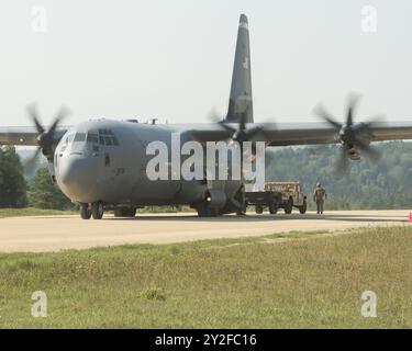 U.S. Army paratroopers assigned to the 173rd Airborne Brigade recover a Humvee with an attached Schutt cargo trailer from a C-130 Hercules aircraft du Stock Photo