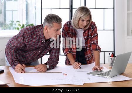 Architects making engineering drawing at wooden table in office Stock Photo