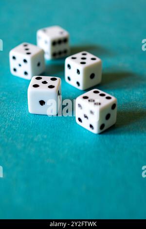 Five dice on a teal background with side lighting. Stock Photo