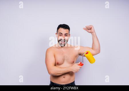Young employee handyman using paint roller hold face isolated on background studio. Stock Photo