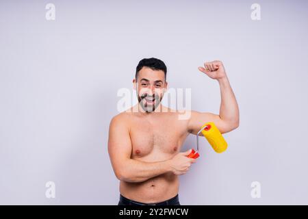 Young employee handyman using paint roller hold face isolated on background studio. Stock Photo