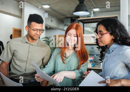 Young professional colleagues in a co-working office reviewing and discussing documents for a project in a work setting Stock Photo