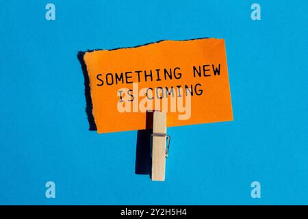 Something new is coming message written on ripped torn orange paper on blue background. Conceptual something new is coming symbol. Copy space. Stock Photo