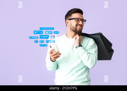 Man with mobile phone and shopping bags chatting online on lilac background Stock Photo