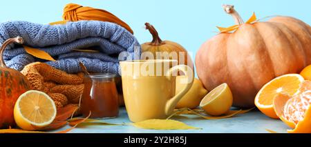 Beautiful autumn composition with cup of tea, citrus fruits, tasty jam and sweaters on light blue background Stock Photo