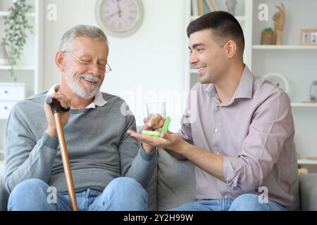 Senior man with his son taking pills at home Stock Photo