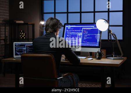 Young male programmer working with computers in office at night Stock Photo