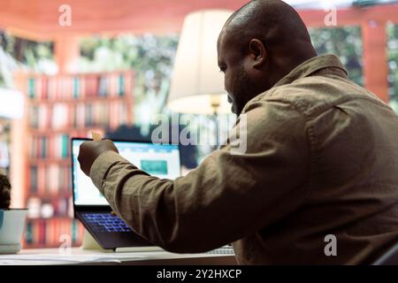 Entrepreneur using a card to make an online shopping payment via electronic banking, purchasing things to help the startup activity. Business owner makes a payment at his home office. Stock Photo