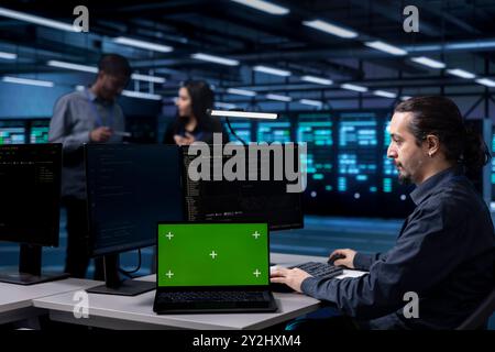 Technician in server hub using green screen tablet to repair equipment storing datasets. IT specialist using mockup device to do debugging on rigs doing computational operations Stock Photo