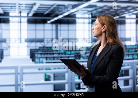 Computer scientist doing disaster recovery planning and security protocol enforcement in data center. IT staff member in server room working to reduce downtime, ensuring business continuity Stock Photo