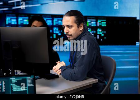 Computer scientists in data center updating systems, protecting servers from damaging software vulnerabilities. Coworkers looking for errors causing infrastructure to slow down Stock Photo