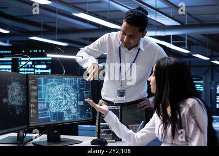 Team of data researchers using AI tech to do checkup in server room providing storage. Teamworking colleagues in data center using PC to enable artificial intelligence to process datasets for training Stock Photo