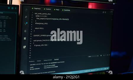 Extreme close up of software interface on PC screens showing lines of code running in empty criminals den. Hacking malware programming script on displays in underground base, handheld camera shot Stock Photo