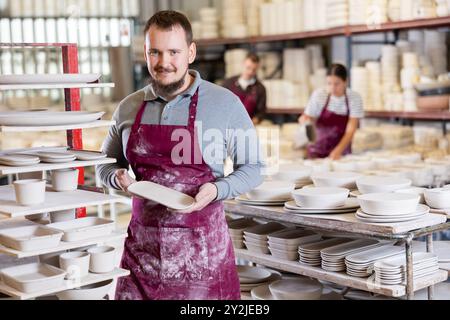 Enthusiastic ceramicist demonstrating handcrafted plates in ceramic studio Stock Photo