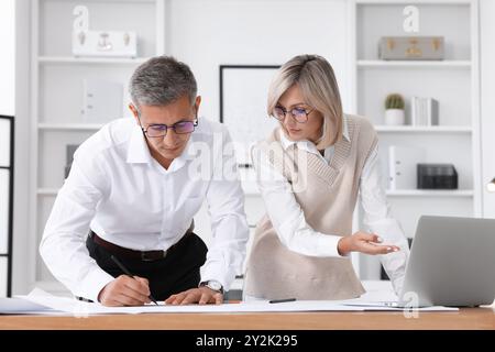 Architects making engineering drawing at wooden table in office Stock Photo
