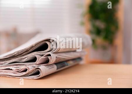Stack of newspapers in different languages on table indoors Stock Photo