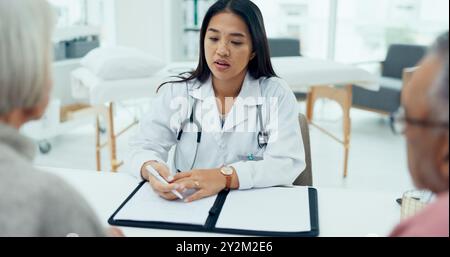 Woman, doctor and writing with elderly couple for checkup, prescription or consultation at hospital. Female person, surgeon or medical employee taking Stock Photo