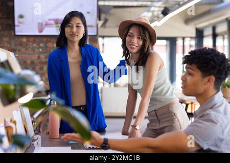 Diverse team collaborating on project, discussing ideas in modern office Stock Photo