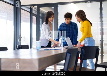 At office, Collaborating on interior design project, diverse team using laptop and discussing ideas Stock Photo