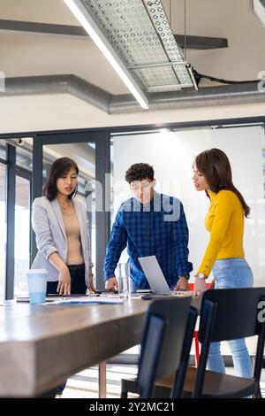 Collaborating on project, diverse team discussing ideas around laptop in office Stock Photo