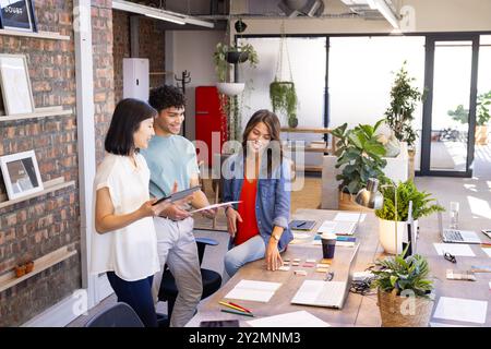 Collaborating on interior design project, diverse team discussing ideas in modern office Stock Photo