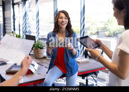 At office, diverse team using digital tablets and blueprints Stock Photo