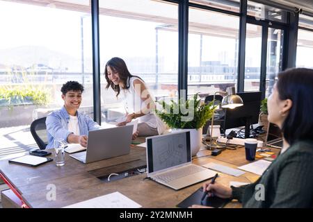 In office, Collaborating on interior design project, diverse team using laptops and discussing plans Stock Photo