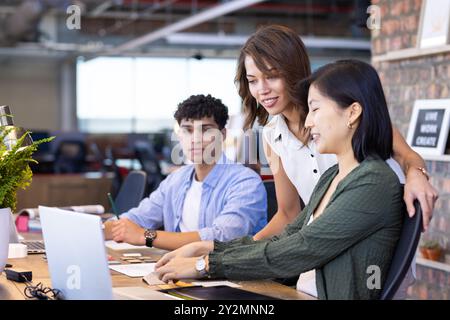 Collaborating on interior design project, diverse team working on laptop in modern office Stock Photo