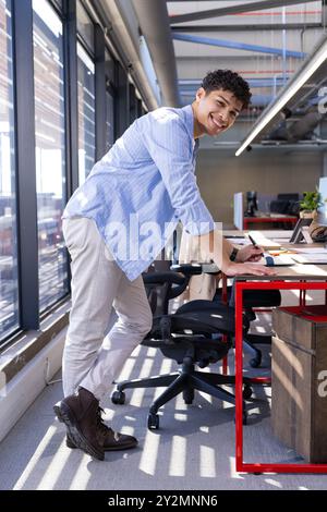 Smiling man standing at desk in modern office, working on design project Stock Photo