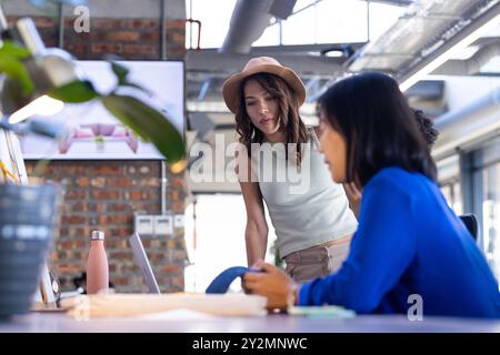 At office, Collaborating on interior design project, diverse team using laptop and discussing ideas Stock Photo