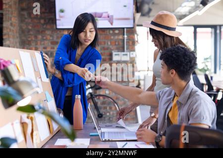 At office, Collaborating on interior design project, diverse team discussing ideas and sharing notes Stock Photo