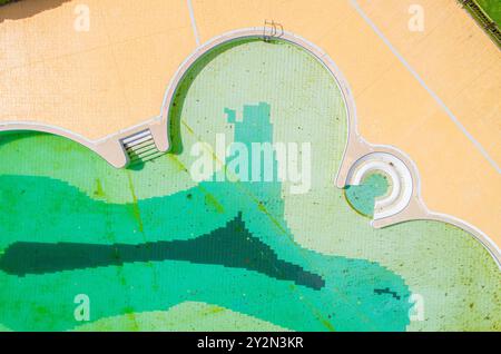 swimming pool without people and with dirty water in autumn after the summer holiday season, aerial top view with a drone. Stock Photo