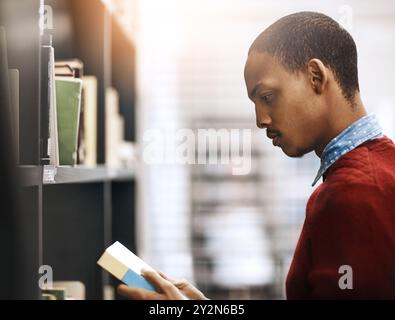 Novel, student and black man reading book in library for education, learning and study at college. Bookshelf, school or male person for research Stock Photo