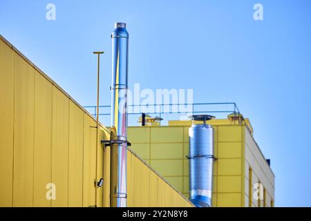 Aluminum composite panels yellow and blue commercial building facade with stainless steel chimney pipe and natural gas duct pipeline of industrial Stock Photo