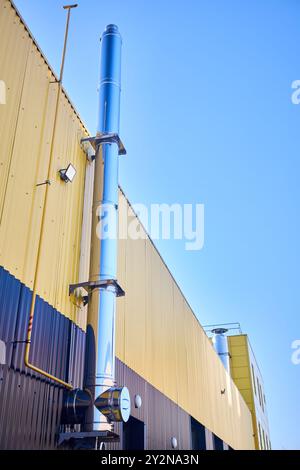 Aluminum composite panels yellow and blue commercial building facade with stainless steel chimney pipe and natural gas duct pipeline of industrial Stock Photo