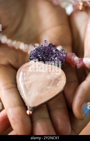 woman holding a rose quartz and amethyst pendant in her hands Stock Photo