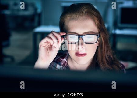 Business, woman and glasses at night on computer at office with deadline, overtime and project as software developer. Employee, face and female person Stock Photo