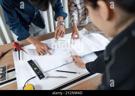 Collaborative Team of Architects Discussing Blueprints and Design Plans at a Modern Office Desk Stock Photo