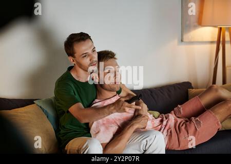 Two men share joy and laughter while cuddling on the couch. Stock Photo