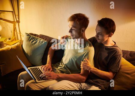 Two men share a tender moment while collaborating at home on a laptop. Stock Photo