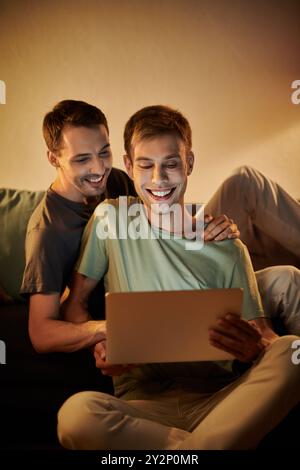 Two men share laughter and joy while watching something together. Stock Photo